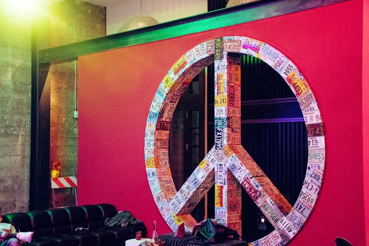 heros-img Vibrant peace sign made of license plates on a red wall, creating a modern artistic atmosphere.
